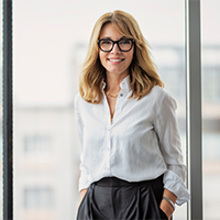 Businessfrau steht lächelnd im Büro – Smart Upgrade unterstützt euch bei Arbeitssicherheit und Dokumentation