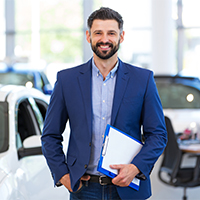 Autoverkäufer steht im Verkaufsraum – Smart Upgrade unterstützt euch bei Unterweisungen und Dokumentationspflichten